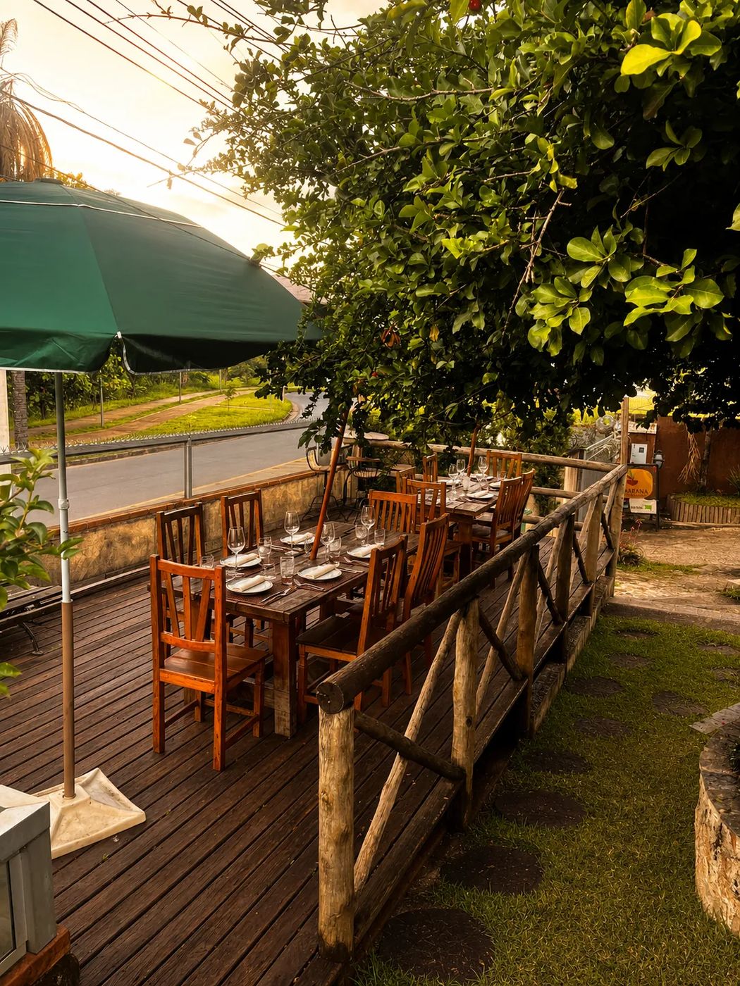 Deck do Sagarana ao pôr do sol, com a mesa posta e o guarda-sol verde