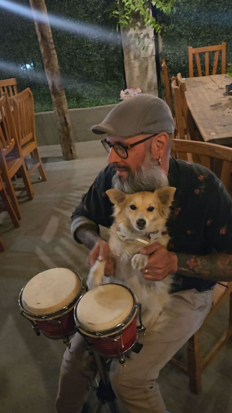 Cachorrinha no colo do dono, ao lado de um bongô